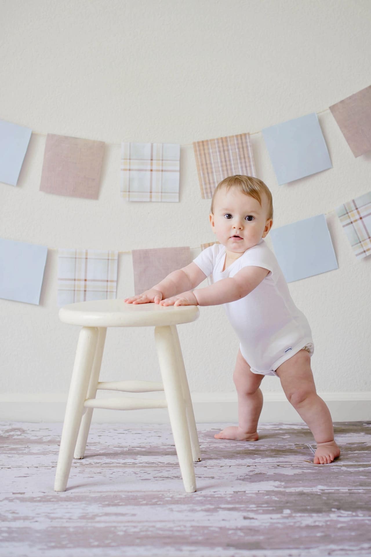 baby is standing leaning on a chair